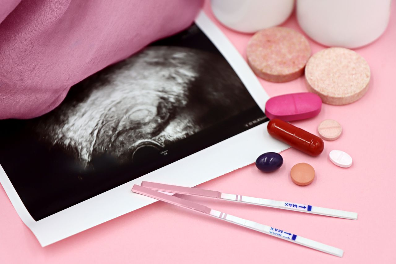 Crafting Captivating Headlines: Your awesome post title goes here A closeup of pregnancy tests and an ultrasound with supplements on a pink background.