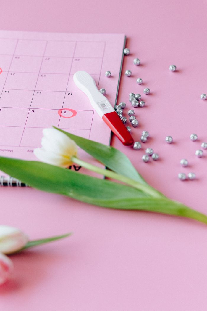 Mastering the First Impression: Your intriguing post title goes here A pregnancy test, tulips, and calendar on pink backdrop conveying anticipation.