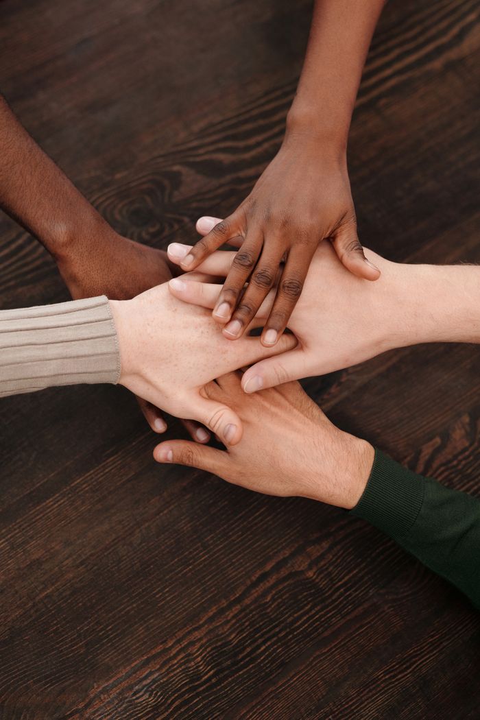 Services Close-up of diverse hands stacked together on wooden surface symbolizing teamwork and unity.